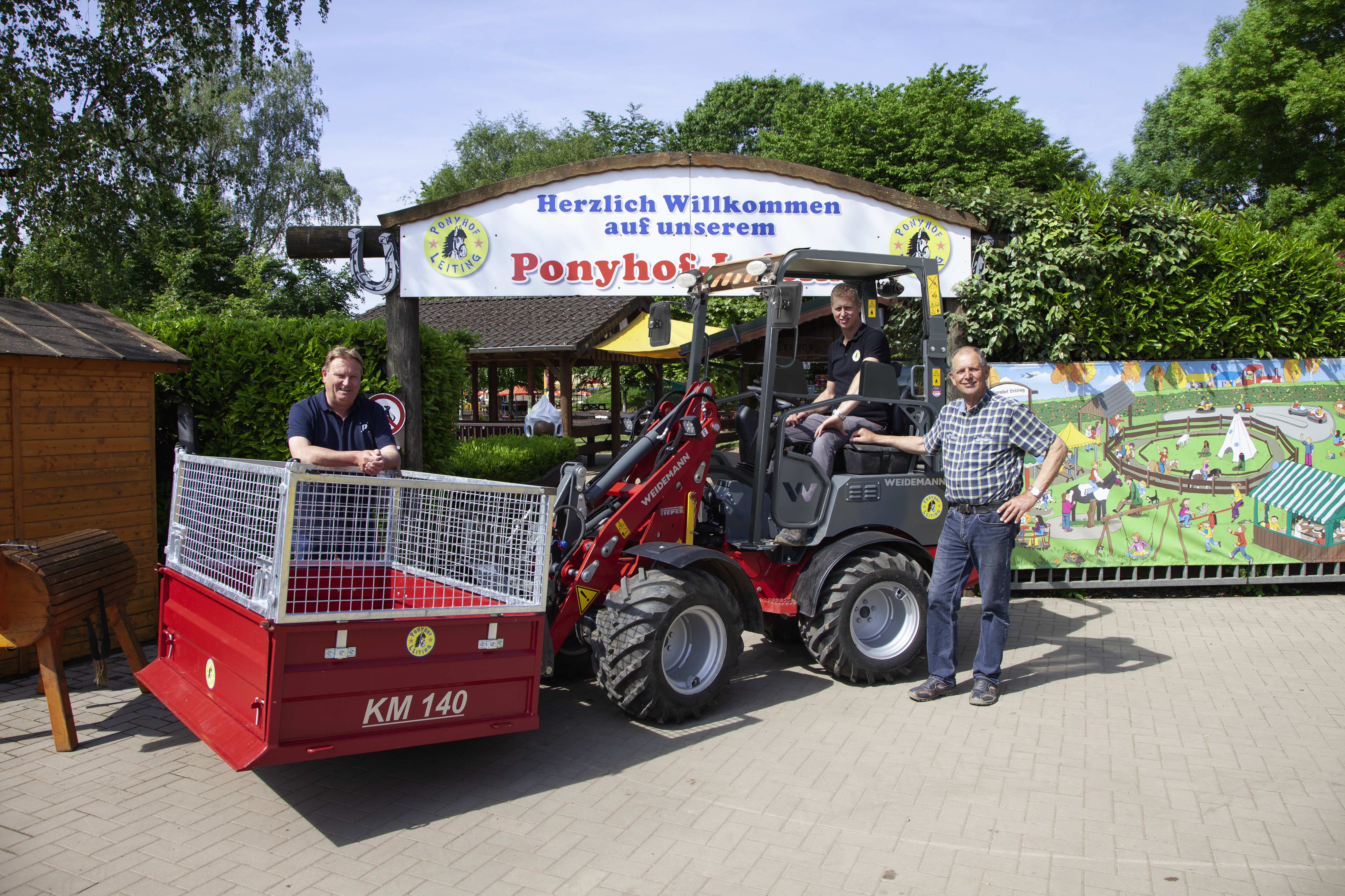 Mehrere Menschen stehen um einen Weidemann Hoftrac 1160e mit Fahrerschutzdach