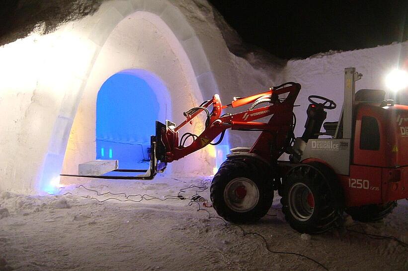 Weidemann Hoftrac 1170 im nächtlichen Einsatz mit einer Palettengabel im Schnee