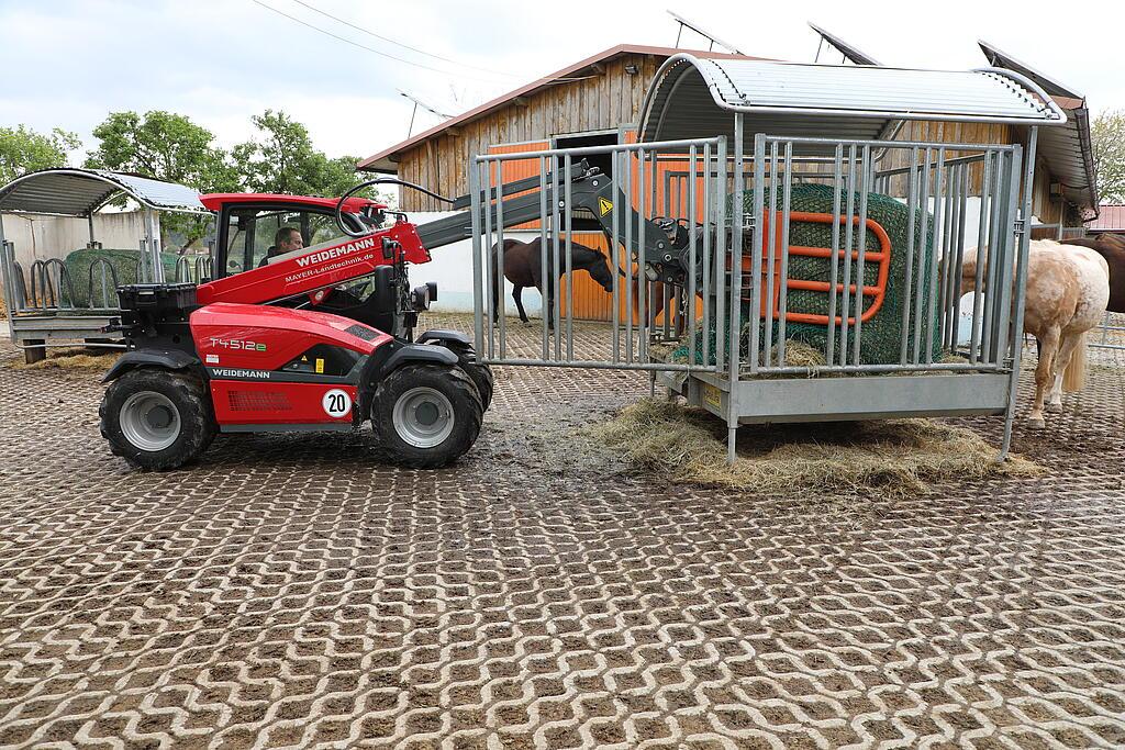 Weidemann Teleskoplader T4512e mit Rundballenzange im Einsatz auf einem Pferdehof