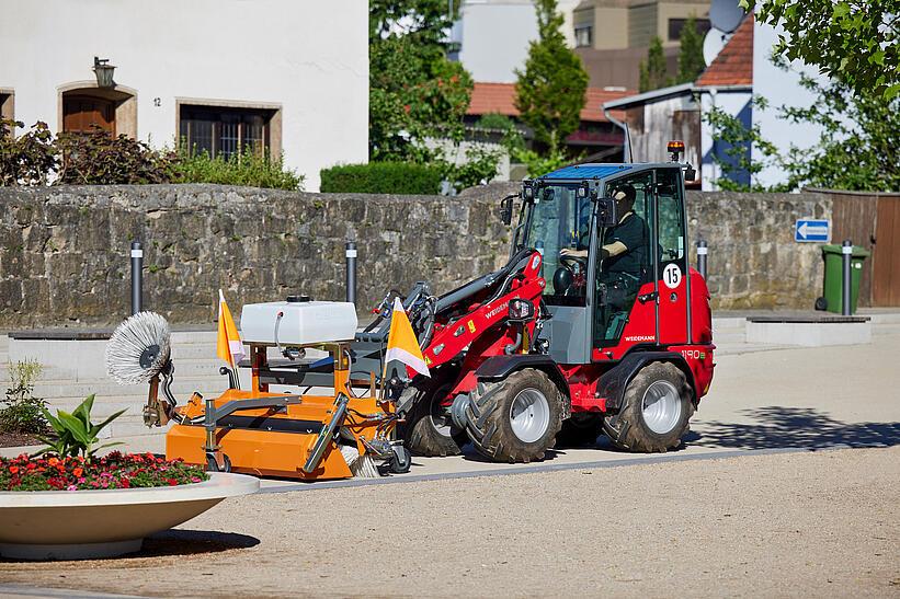 Weidemann Hoftrac 1190e mit Kabine im Einsatz mit Kehrmaschine